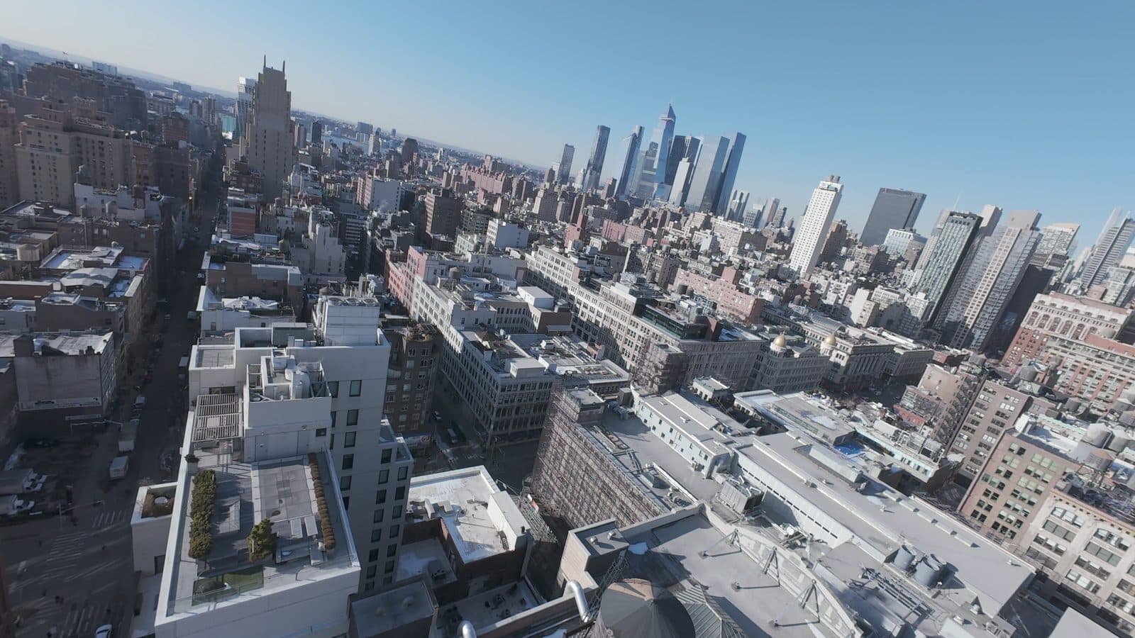 Aerial view across Manhattan rooftops toward the midtown skyline, filmed by an AVP.Live drone operator
