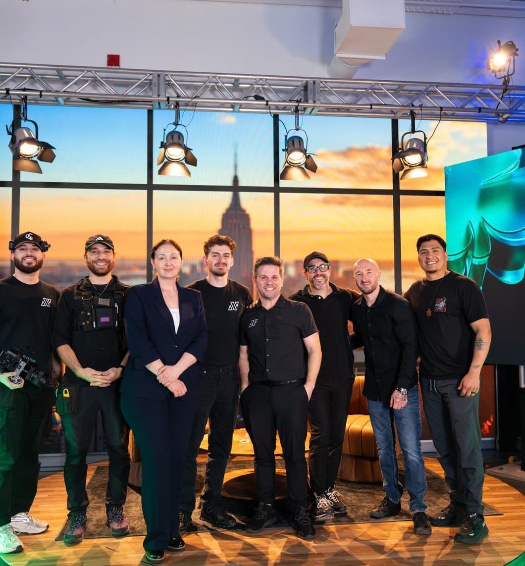 The AVP.Live crew on set in front of a Manhattan skyline LED wall, standing on the round stage they built for a live broadcast